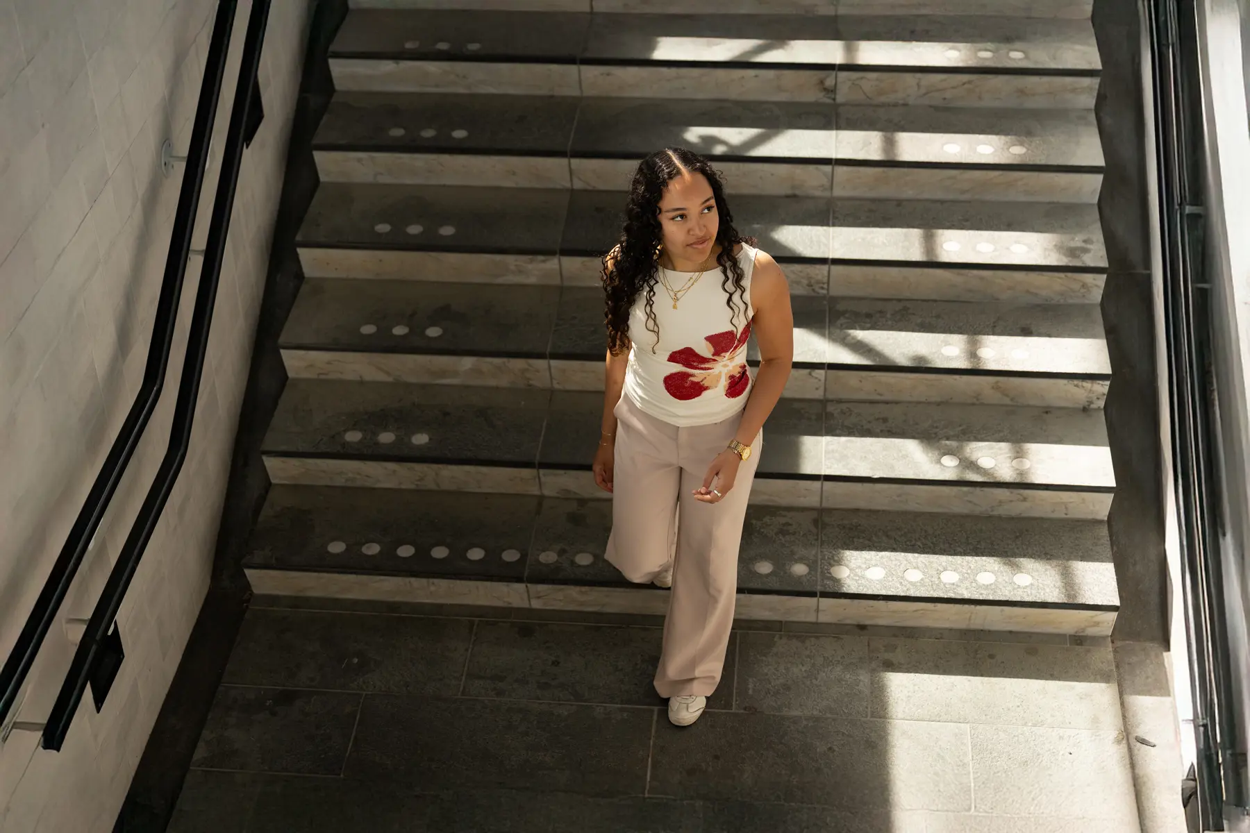 Ishani loopt op de trap van een station naar beneden. Het is zonnig en vrolijk. 